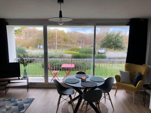 - un salon avec une table, des chaises et une grande fenêtre dans l'établissement Résidence goulvars., à Quiberon