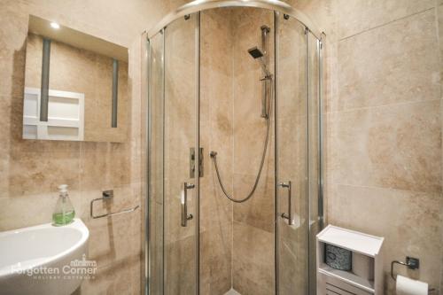 a shower with a glass door in a bathroom at Kelvin House - Cawsand in Cawsand