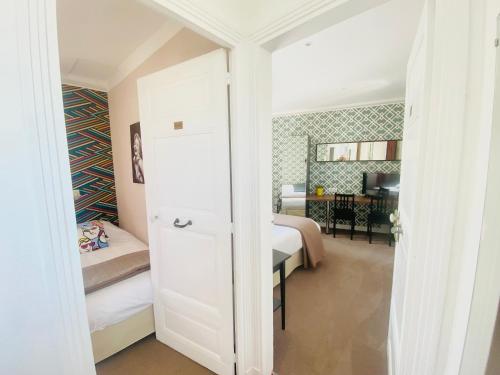 a small bedroom with a bed and a desk at Grand Hôtel de L'Espérance in Lisieux