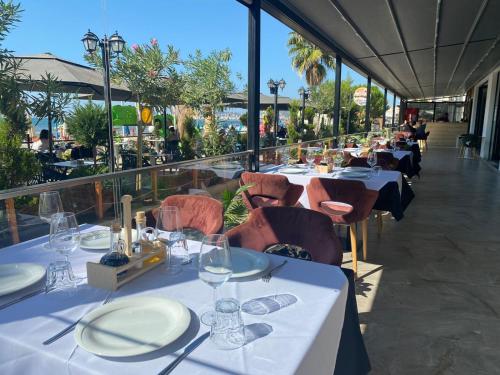 un restaurant avec des tables et des chaises, des assiettes et des verres blancs dans l'établissement Hotel Alion, à Durrës