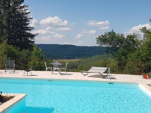 a swimming pool with two chairs and a table and chairs at Maison de Vacances in Tursac