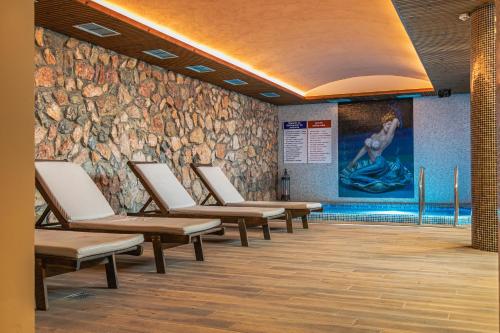 a row of chairs in a waiting room with a stone wall at Hotel & Spa Tino Sveti Stefan in Ohrid