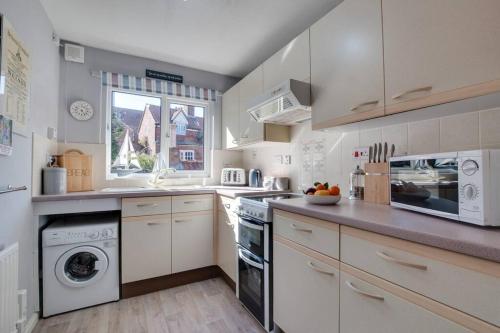 a large kitchen with white cabinets and a window at Abbey View Bagdale in the Centre of Whitby in Whitby