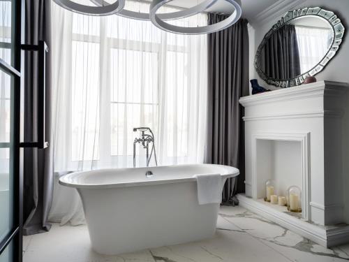 a white bath tub in a bathroom with a chandelier at Бутик-отель 39 by SATEEN GROUP in Rostov on Don