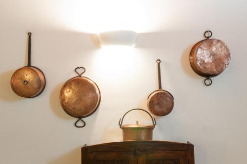 four copper pots and pans hanging on a wall at Collerovere Country House in SantʼAngelo in Pontano