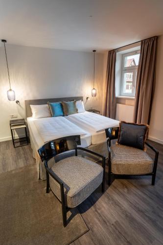 a bedroom with a large bed and two chairs at Hotel Weißes Ross in Kulmbach