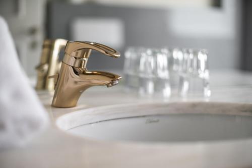 a bathroom sink with a gold faucet at Hotel Parks in Velden am Wörthersee