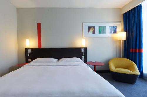 a bedroom with a large bed and a yellow chair at Park Inn by Radisson Hotel Astana in Astana