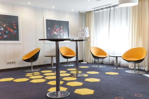 a room with yellow chairs and a table and a rug at Park Inn by Radisson Hotel Astana in Astana