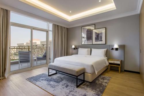 a bedroom with a large bed and a balcony at Radisson Hotel Riyadh Airport in Riyadh