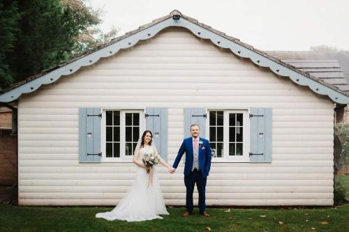 a bride and groom standing in front of a white shed at Slaters Country Inn in Whitmore
