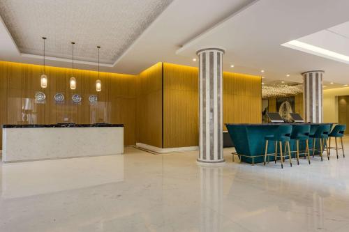 a lobby with a bar with blue chairs and columns at Radisson Hotel Riyadh Airport in Riyadh