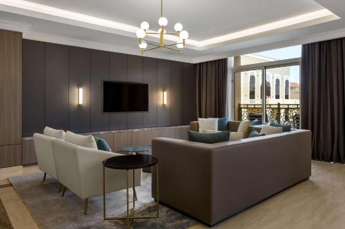 a living room with a couch and chairs and a tv at Radisson Hotel Riyadh Airport in Riyadh