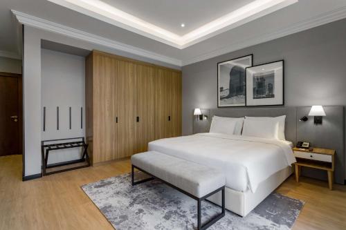 a bedroom with a large white bed and a bench at Radisson Hotel Riyadh Airport in Riyadh