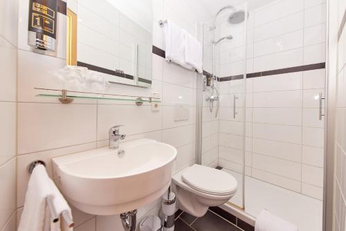 a white bathroom with a sink and a toilet at Hotel-Restaurant Ehses in Zeltingen-Rachtig