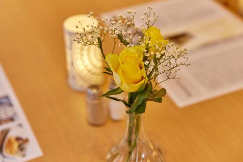 a vase with yellow roses in it on a table at Hotel-Restaurant Ehses in Zeltingen-Rachtig