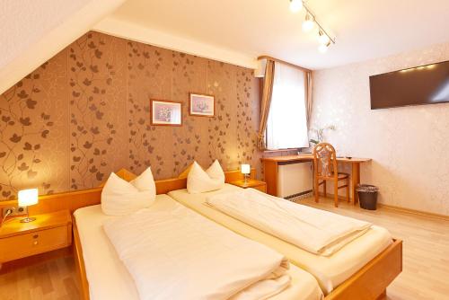 a hotel room with two beds and a desk at Hotel-Restaurant Ehses in Zeltingen-Rachtig