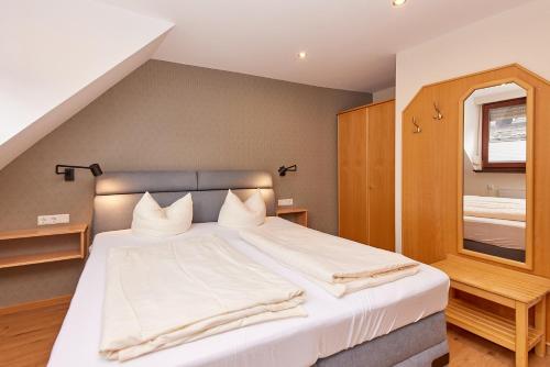 a bedroom with a large bed with white sheets at Hotel-Restaurant Ehses in Zeltingen-Rachtig
