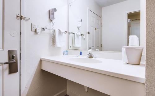 Sky-Palace Inn & Suites McCook في ماكوك: حمام أبيض مع حوض ومرآة