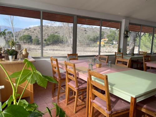 ein Esszimmer mit einem Tisch, Stühlen und Fenstern in der Unterkunft Hotel Rural El Arca de Noé in El Tiemblo