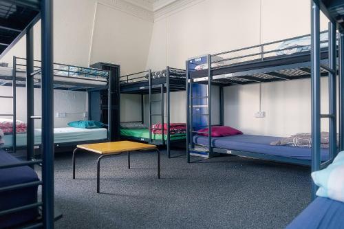 a room with three bunk beds and a table at Princes Street Hostel in Edinburgh