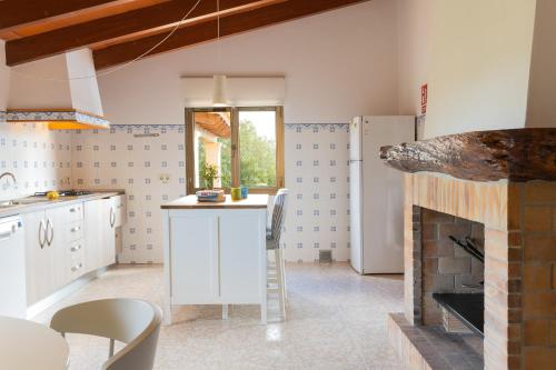 a kitchen with a fireplace and a table and a refrigerator at Villa Sa Tanca in Campos