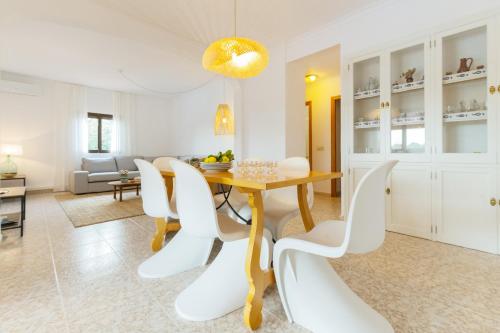 a dining room with a table and white chairs at Villa Sa Tanca in Campos