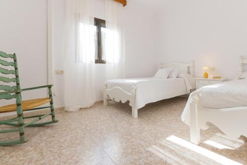 a white bedroom with two beds and a chair at Villa Sa Tanca in Campos