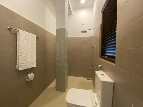 a bathroom with a white toilet and a shower at Dimuthu Home in Ambalangoda