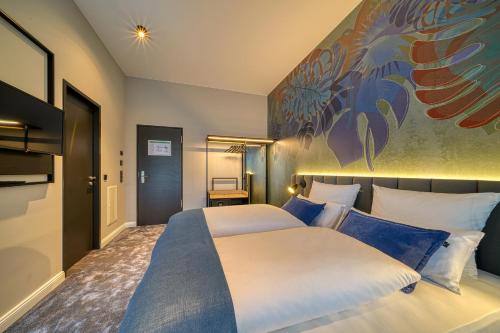 a bedroom with two beds and a painting on the wall at Vienna House Easy by Wyndham Bonn City in Bonn