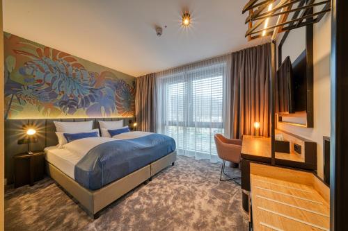 a hotel room with a bed and a desk and a television at Vienna House Easy by Wyndham Bonn City in Bonn