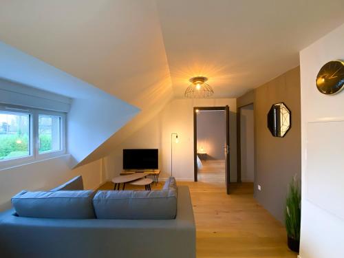 un soggiorno con divano blu e TV di WHITE HOUSE DHAVERNAS - PROCHE CENTRE - PARKING - WIFi HD ad Amiens