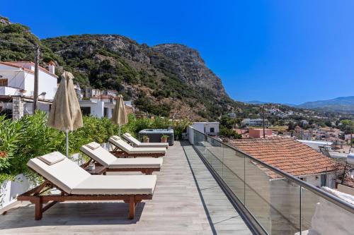 a row of lounge chairs on a balcony with mountains at Casa Sofia, By Hellocrete in Spílion