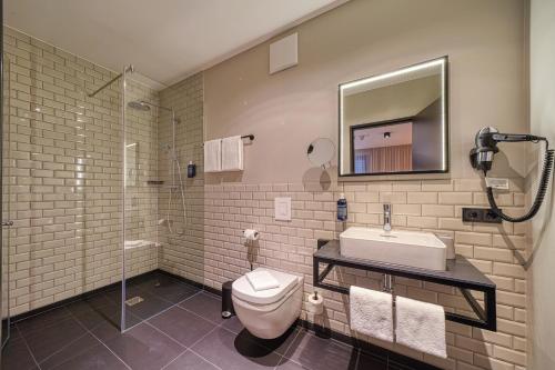 a bathroom with a toilet and a sink at NYCE Hotel Bonn in Bonn