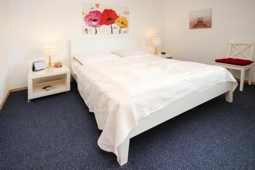 um quarto com uma grande cama branca e duas mesas em Apartment captain's cabin, Dornumersiel em Dornumersiel