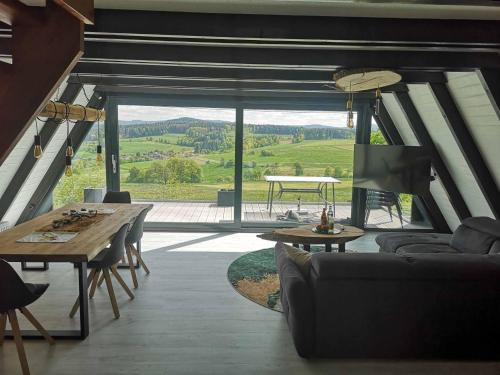 a living room with a table and a large window at Ferienhaus Fynnhütte in Schwarzenborn