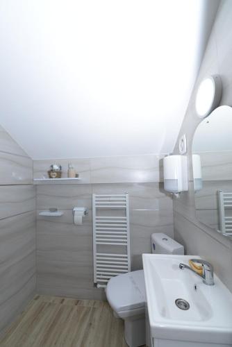 a white bathroom with a sink and a toilet at Casa Teo&Andreea in Vatra Dornei