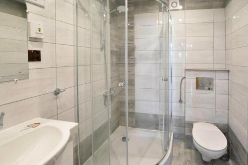 a bathroom with a shower and a toilet and a sink at Wooden House by Ostrowieckie Lake with Beach in Kosierzewo
