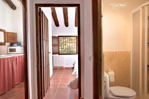a bathroom with a toilet and a hallway at La Casa del Agua in Montefrío