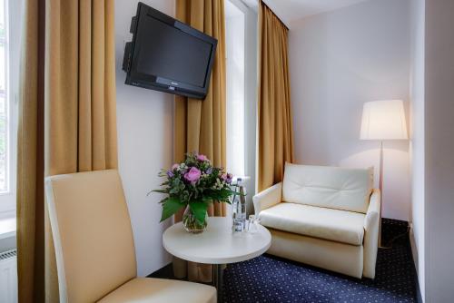 a room with a chair and a table with a tv at Hotel Fürst Bismarck in Hamburg