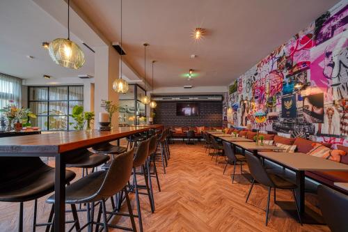 a restaurant with tables and chairs and a wall of graffiti at Vienna House Easy by Wyndham Bonn City in Bonn