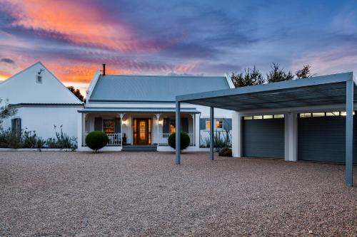 a white house with a garage at sunset at Karoo Masterclass House and Karoo Masterclass Cottage - Accommodation Prince Albert in Prince Albert