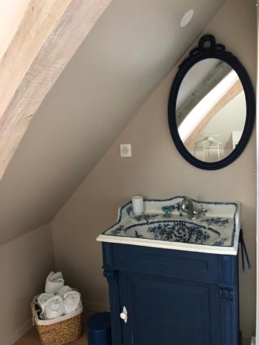 ein Bad mit einem Waschbecken und einem Spiegel in der Unterkunft Au gré des saisons in Héricourt