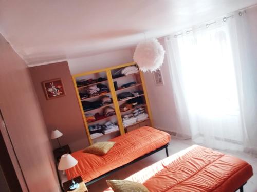 1 dormitorio con banco de naranja y armario en Maison Berrichonne avec cour et jardin intime, en Saint-Marcel