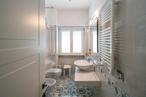 La salle de bains est pourvue de 2 lavabos et de 2 toilettes. dans l'établissement Park Hotel Villa Maria, à San Menaio