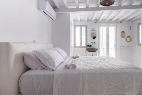 een witte slaapkamer met een wit bed en 2 handdoeken erop bij aníko suites Chora in Mykonos-stad
