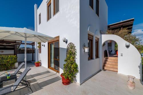 a patio with chairs and an umbrella next to a building at Evilion Villa in Gennadi