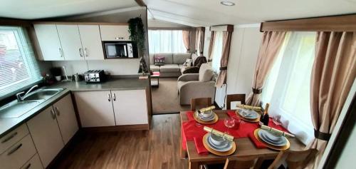 a kitchen and living room with a table in a caravan at 5 Geranium, Holiday Home in Oakdene Forest Park in Ferndown