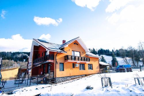 a house in the snow with a car parked at Casa Teo&Andreea in Vatra Dornei