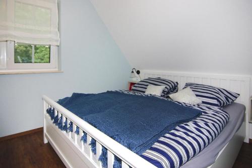 1 dormitorio con 1 cama con almohadas de rayas azules y blancas en Holiday home my anchorage, Zirchow, en Zirchow